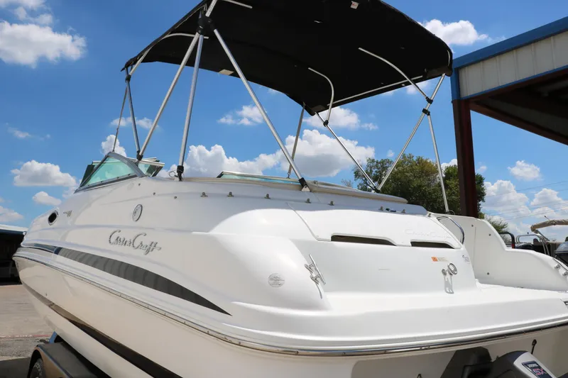 Slide: The Image of 2000 Chris-Craft 232 boat with canopy, docked under blue sky. - 8