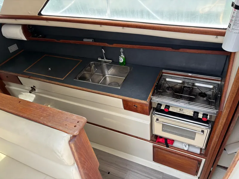 Slide: The Image of 1999 Gemini 105M boat kitchen with sink, stove, and wooden cabinetry. - 8