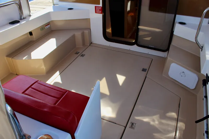 Slide: The Image of 2011 Ranger Tugs R-27 boat interior with red seating and spacious deck area. - 14