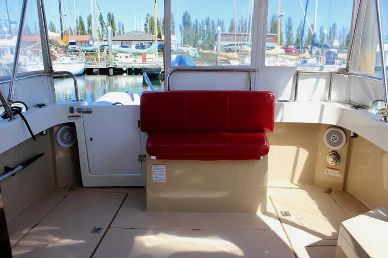 Slide: The Image of 2011 Ranger Tugs R-27 boat interior with red seating and marina view. - 15