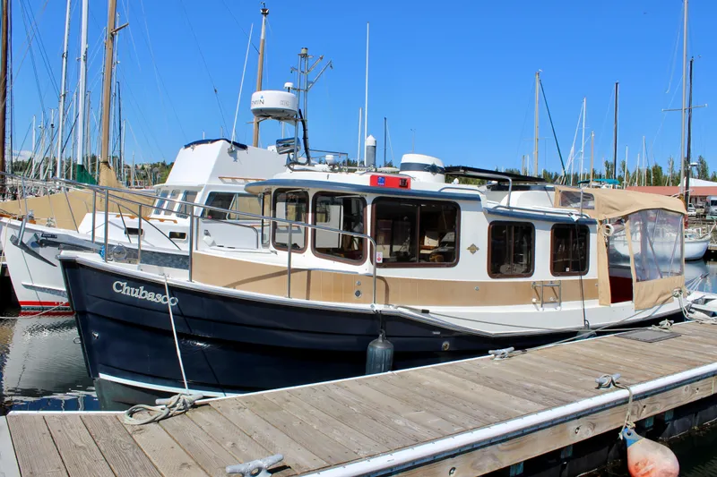 Slide: The Image of 2011 Ranger Tugs R-27 boat docked at marina under clear blue sky. - 2