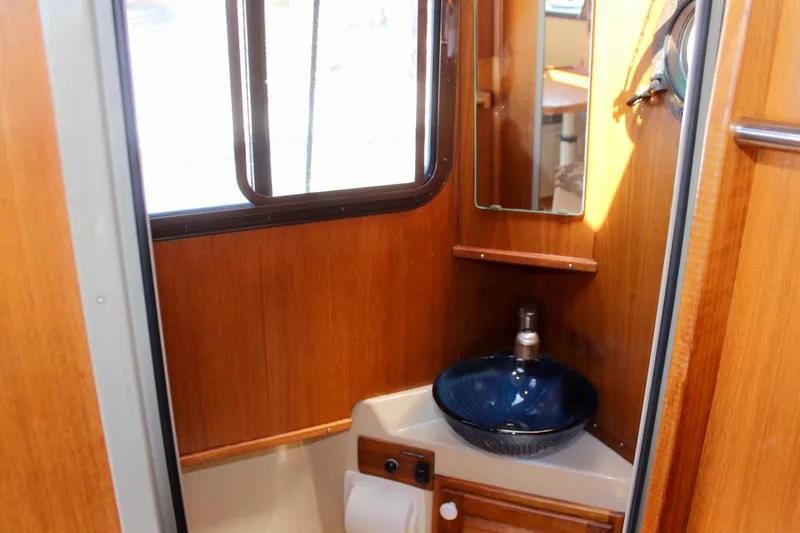 Slide: The Image of Compact bathroom interior of 2011 Ranger Tugs R-27 with wooden finish and blue sink. - 20