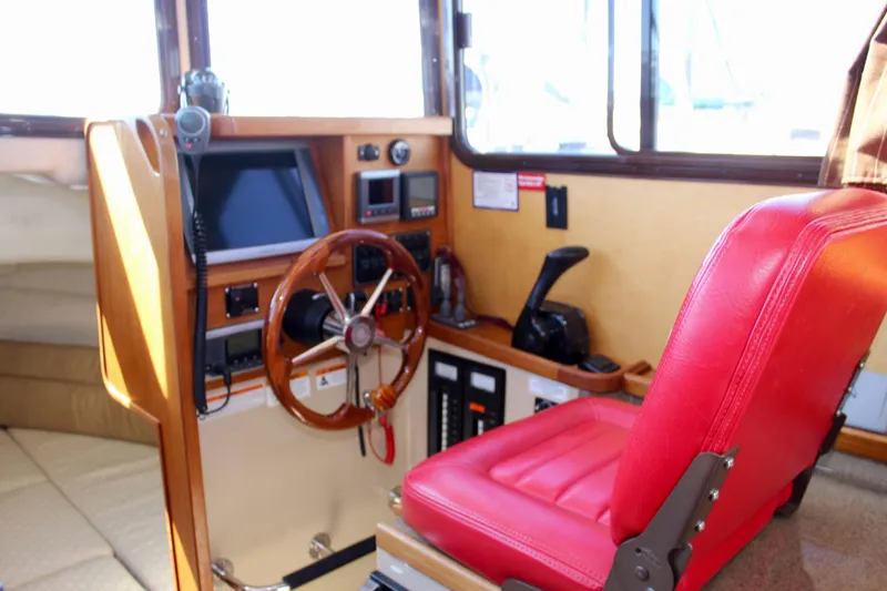 Slide: The Image of Interior of 2011 Ranger Tugs R-27 boat with red captain's chair and wooden steering wheel. - 30