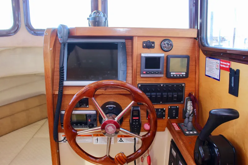 Slide: The Image of 2011 Ranger Tugs R-27 helm with wooden steering wheel and navigation instruments. - 31