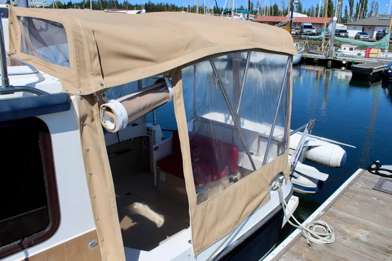Slide: The Image of 2011 Ranger Tugs R-27 boat with tan canopy docked at marina. - 5