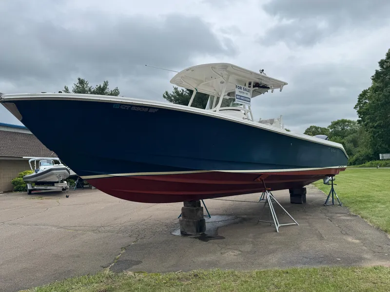 The Image of 2013 Edgewater 318CC boat on stands, displayed outdoors on a cloudy day. - 0