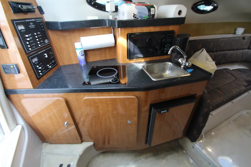 Slide: The Image of 2004 Regal 2665 Commodore boat interior with kitchenette, sink, and seating area. - 16