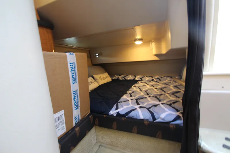 Slide: The Image of 2004 Regal 2665 Commodore cabin with bed, cozy interior, and soft lighting. - 17