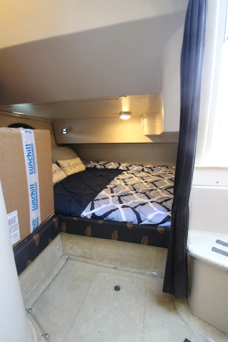 Slide: The Image of 2004 Regal 2665 Commodore cabin with bed, storage, and natural light. - 18