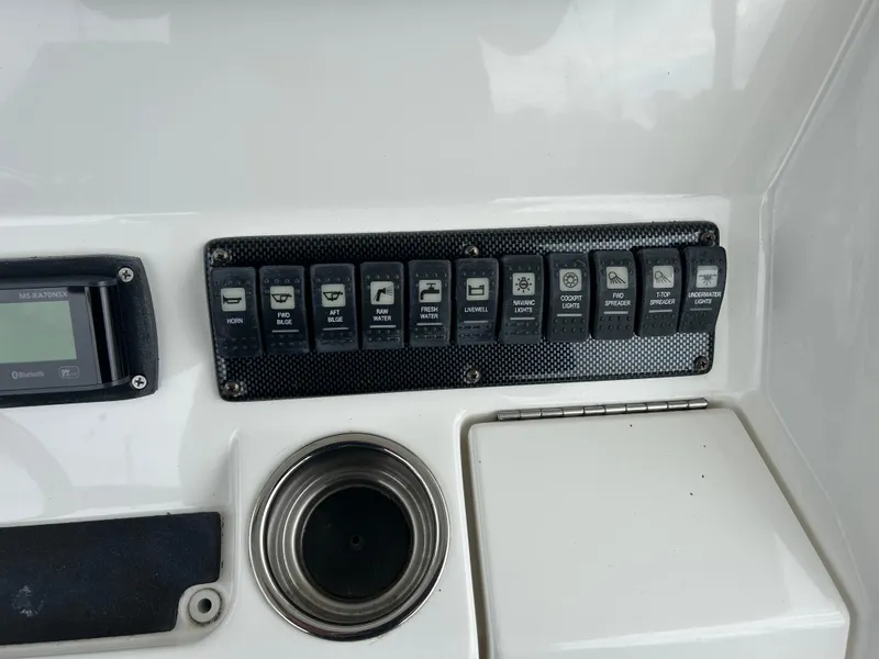 Slide: The Image of Control panel of a 2014 Regulator 34 boat with multiple switches and cup holder. - 14