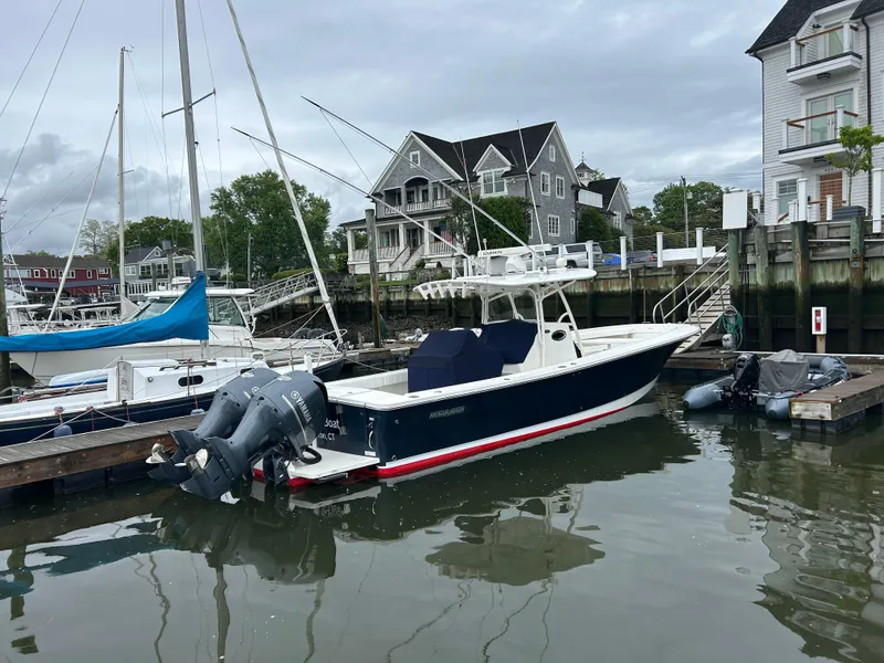 Slide: The Image of 2014 Regulator 34 boat docked in a marina, surrounded by other vessels. - 2