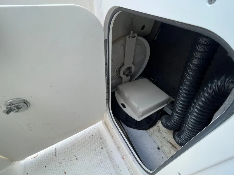 Slide: The Image of Storage compartment in 2018 Chaparral Vortex 243 boat, featuring coiled hoses and a seat cushion. - 18
