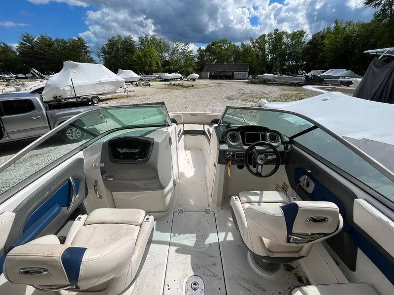 Slide: The Image of 2018 Chaparral Vortex 243 boat interior with seating and steering wheel, parked outdoors. - 7