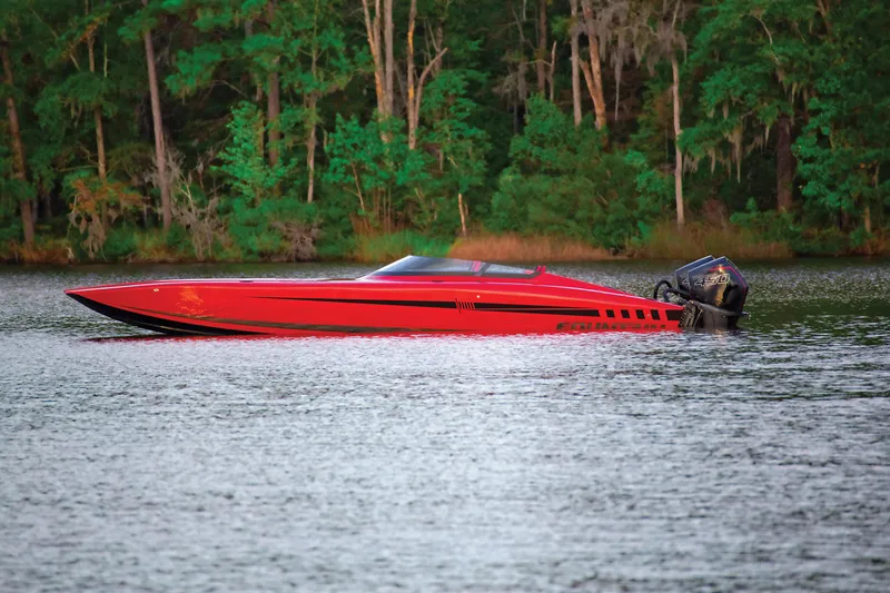 Slide: The Image of 2025 Fountain 34 Thundercat boat on a serene lake with lush green forest backdrop. - 2