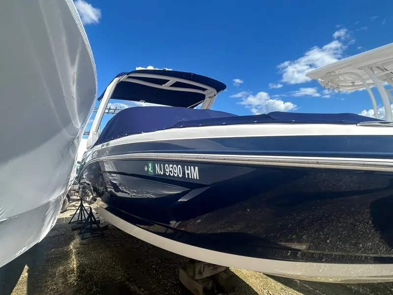 Slide: The Image of 2019 Chaparral 250 Suncoast boat with blue hull, docked under clear sky. - 2