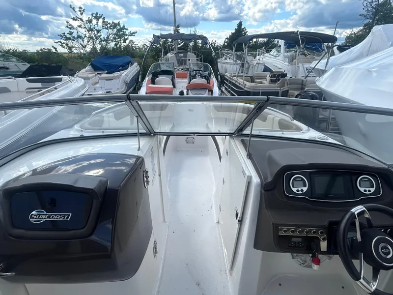 Slide: The Image of 2019 Chaparral 250 Suncoast boat interior with dashboard and steering wheel, docked among other boats. - 30