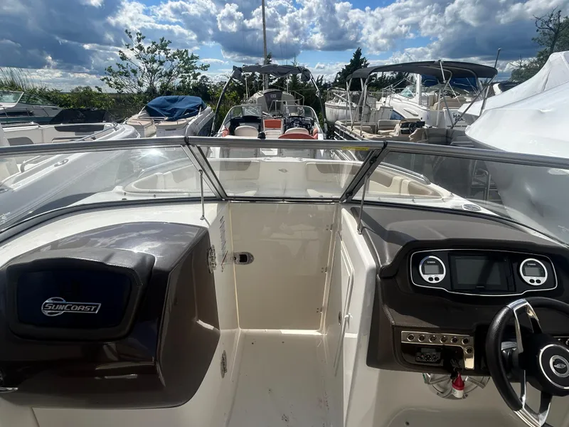 Slide: The Image of 2019 Chaparral 250 Suncoast boat interior with steering wheel and dashboard, docked under cloudy sky. - 31