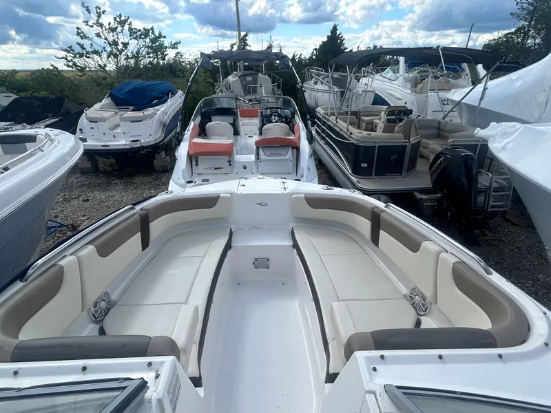 Slide: The Image of 2019 Chaparral 250 Suncoast boat with spacious seating, docked among other boats. - 32