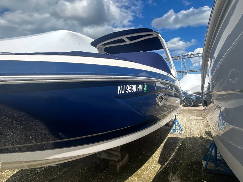 Slide: The Image of 2019 Chaparral 250 Suncoast boat in storage, blue hull, clear sky background. - 4