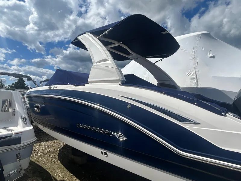 Slide: The Image of 2019 Chaparral 250 Suncoast boat with blue and white exterior under a cloudy sky. - 5