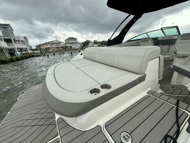 Slide: The Image of 2022 Sea Ray SLX 280 boat with spacious seating and cup holders, docked by waterfront homes. - 12