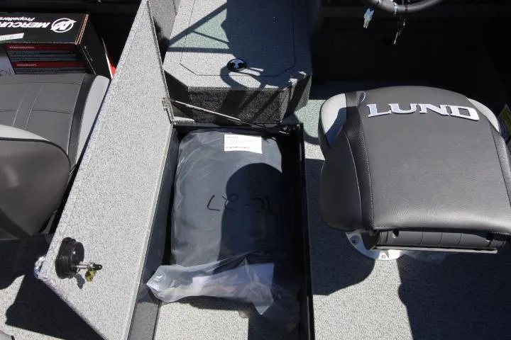 Slide: The Image of 2025 Lund 1775 Crossover XS boat interior with storage compartment and branded seat. - 9