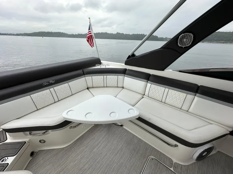 Slide: The Image of 2017 Sea Ray SLX 280 boat interior with seating and table, on a calm lake. - 17