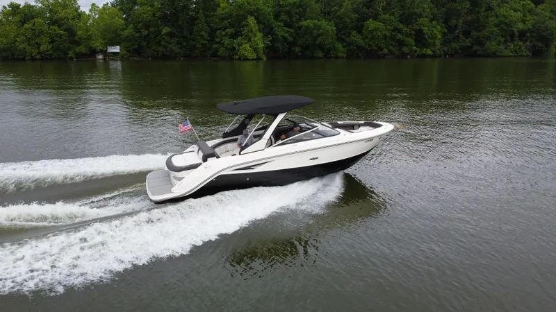 Slide: The Image of 2017 Sea Ray SLX 280 boat cruising on a lake with lush green trees. - 2