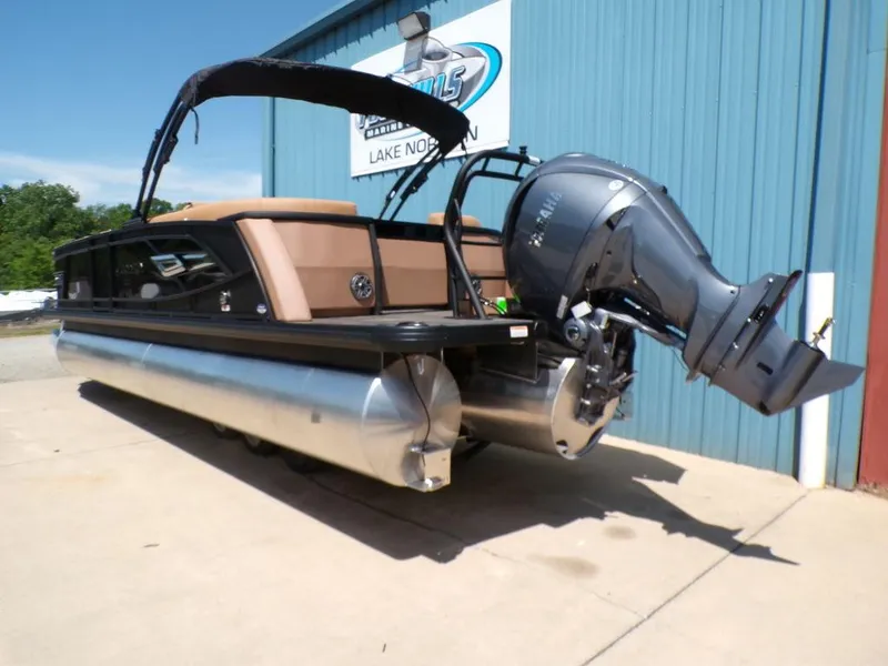 Slide: The Image of 2025 Godfrey AquaPatio 235 SBC pontoon boat with outboard motor, docked near blue building. - 13