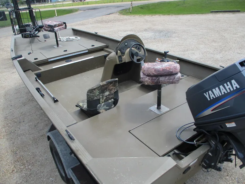 Slide: The Image of Aluminum fishing boat with Yamaha motor, featuring camo seats and steering console, parked on gravel. - 9