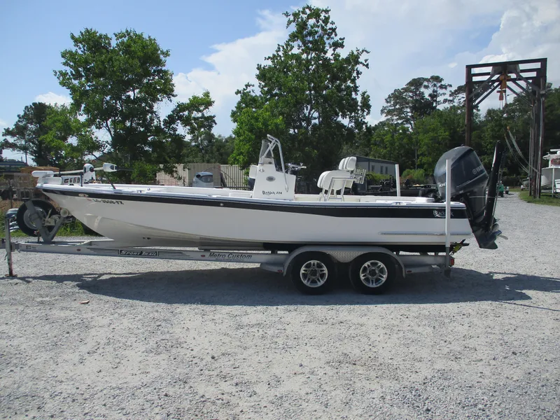 Slide: The Image of 2010 BlackJack 224 boat on trailer, parked on gravel, with trees in background. - 0