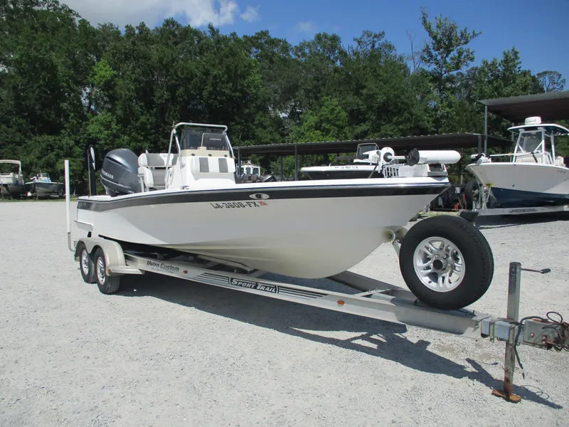 Slide: The Image of 2010 BlackJack 224 boat on trailer in outdoor lot, surrounded by trees and other boats. - 3