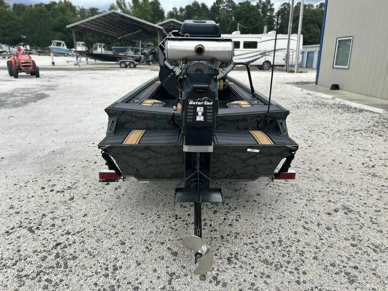 Slide: The Image of 2025 Gator Tail EXTREME MOD-V 1854 boat with outboard motor, parked on gravel. - 1