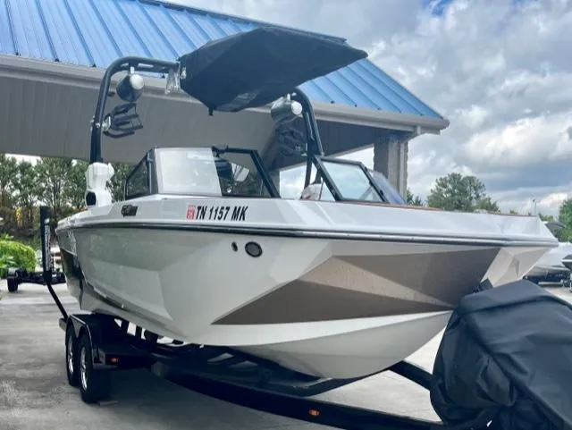 Slide: The Image of 2023 Nautique Super Air Nautique GS22 boat on trailer under blue roof. - 2
