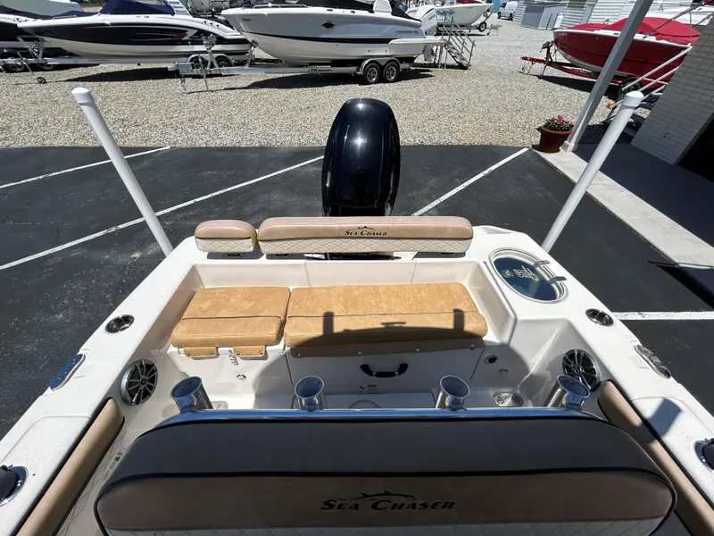 Slide: The Image of 2023 Sea Chaser 22 HFC boat interior with seating and motor, parked in a lot. - 16