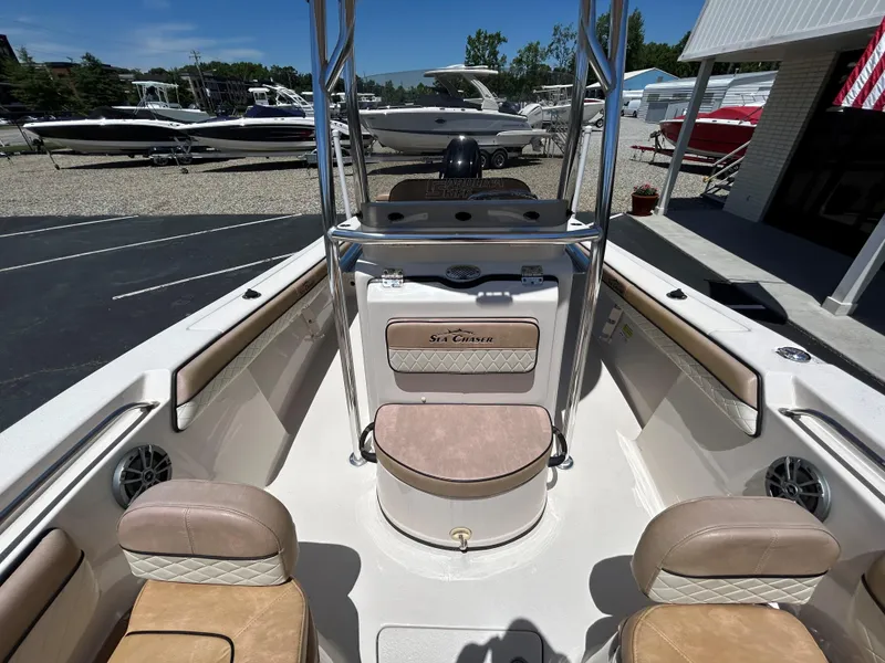 Slide: The Image of 2023 Sea Chaser 22 HFC boat interior with seating and console, displayed at a marina. - 18