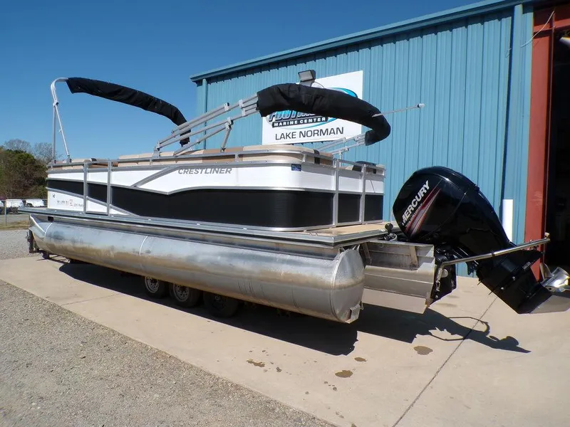 Slide: The Image of 2018 Crestliner 220 RALLY pontoon boat with Mercury outboard motor, parked near a blue building. - 19