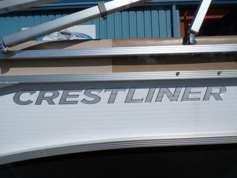 Slide: The Image of 2018 Crestliner 220 RALLY boat with logo detail, docked near a blue building. - 21