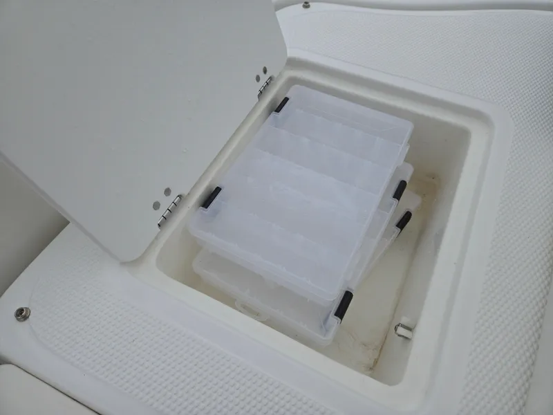 Slide: The Image of Storage compartment with plastic containers in a 2019 Tahoe 500 TF boat. - 24