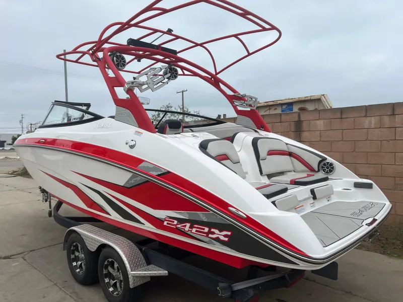 Slide: The Image of 2020 Yamaha Boats 242X in red and white on a trailer, parked outdoors. - 5