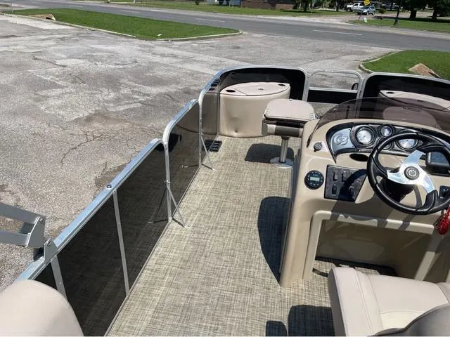 Slide: The Image of 2019 SunCatcher V 322CC boat interior with steering wheel and seating, parked on pavement. - 13