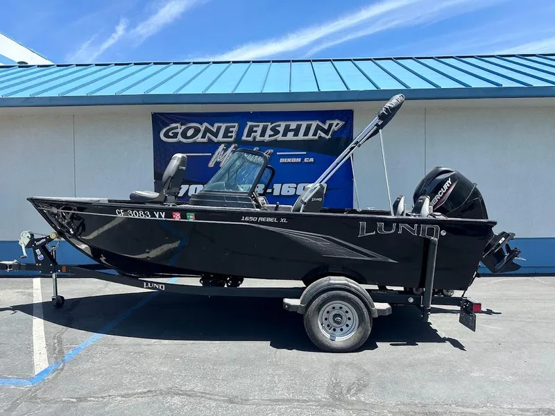 Slide: The Image of 2022 Lund 1650 Rebel XL Sport boat on trailer, parked outside a building. - 1