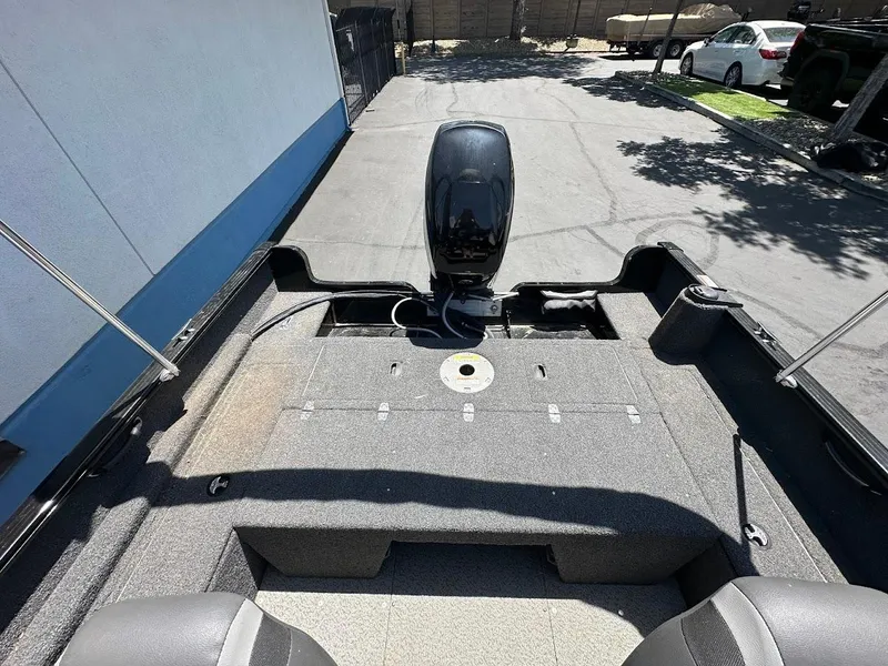 Slide: The Image of 2022 Lund 1650 Rebel XL Sport boat interior with motor, parked outdoors. - 12