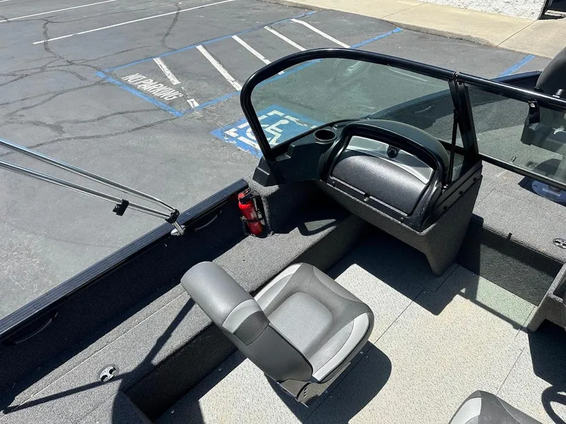 Slide: The Image of 2022 Lund 1650 Rebel XL Sport boat interior with seating and windshield in a parking lot. - 14