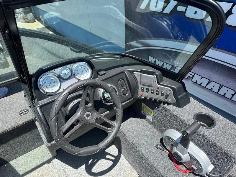 Slide: The Image of 2022 Lund 1650 Rebel XL Sport boat dashboard with steering wheel and control panel. - 16