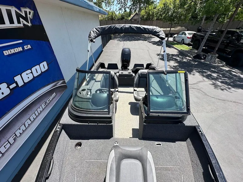 Slide: The Image of 2022 Lund 1650 Rebel XL Sport boat with dual consoles and seating, parked outdoors. - 21