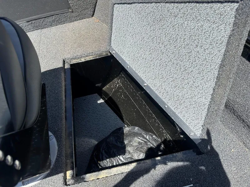 Slide: The Image of 2022 Lund 1650 Rebel XL Sport boat storage compartment open, showing interior space. - 28