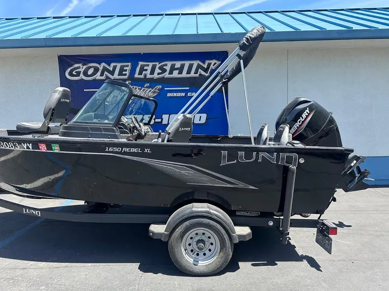 Slide: The Image of 2022 Lund 1650 Rebel XL Sport boat on trailer, parked outside a fishing store. - 8
