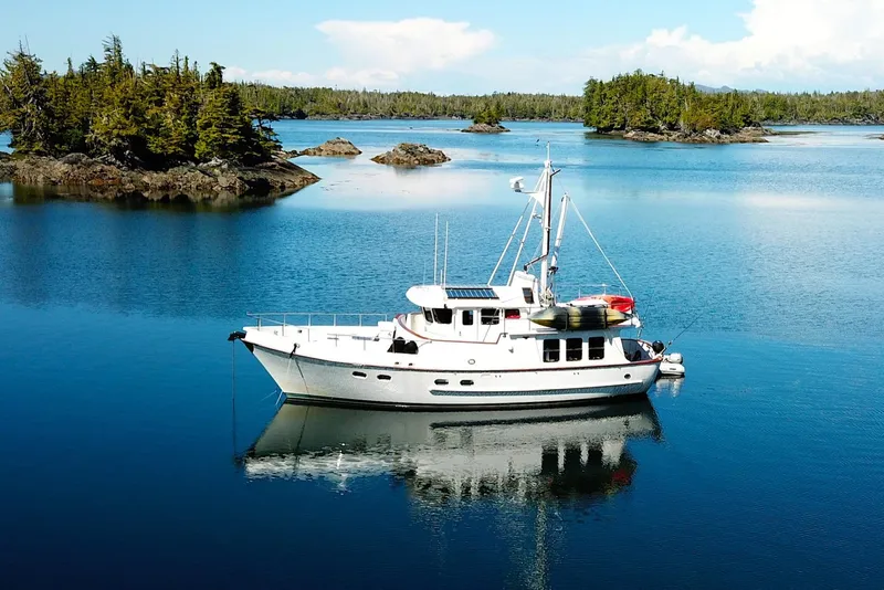 The Image of Nordhavn N46 yacht from 2003 anchored in a serene, forested bay. - 0