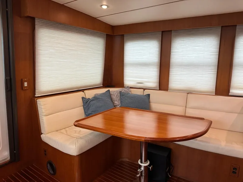Slide: The Image of Cozy dining area in 2003 Nordhavn N46 yacht with wooden table and cushioned seating. - 14